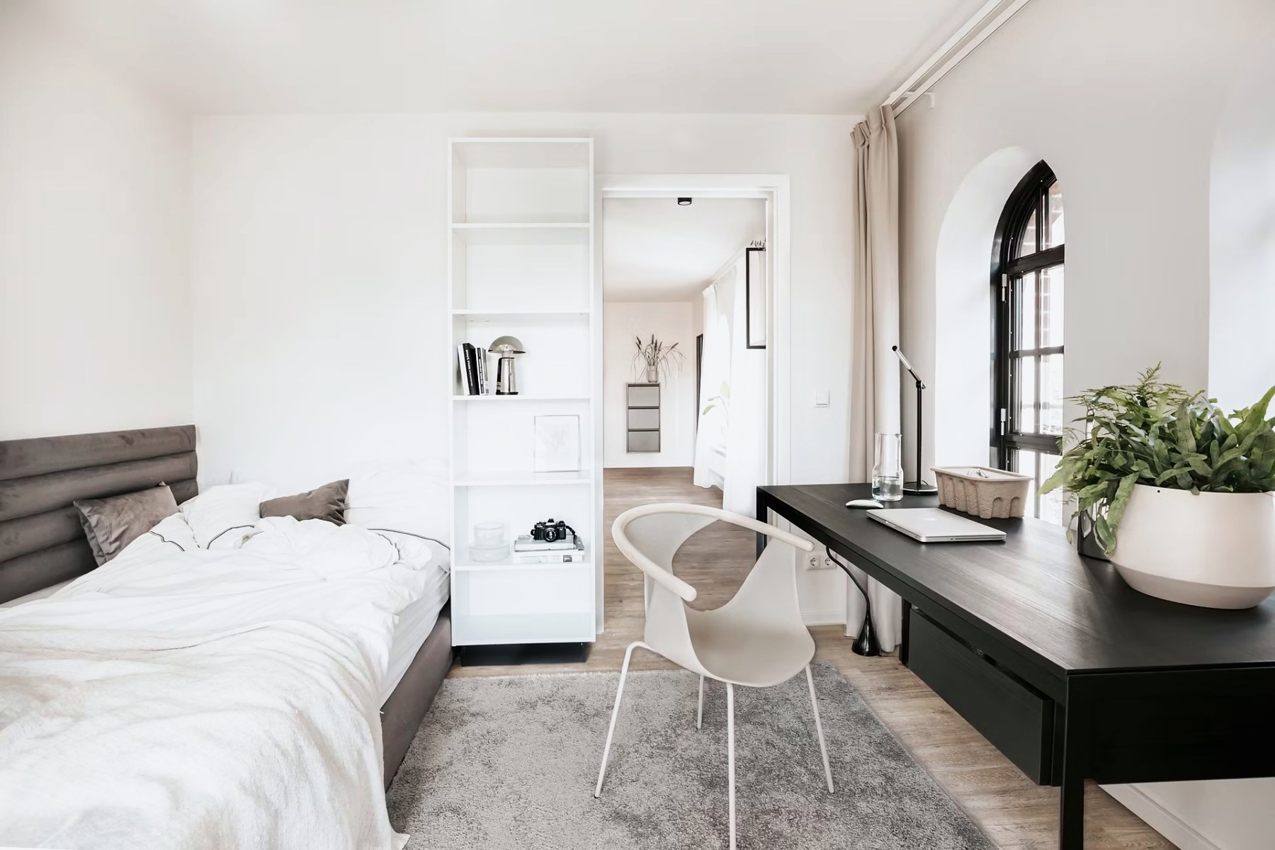 Schlafzimmer mit Bett und Schreibtisch am Fenster