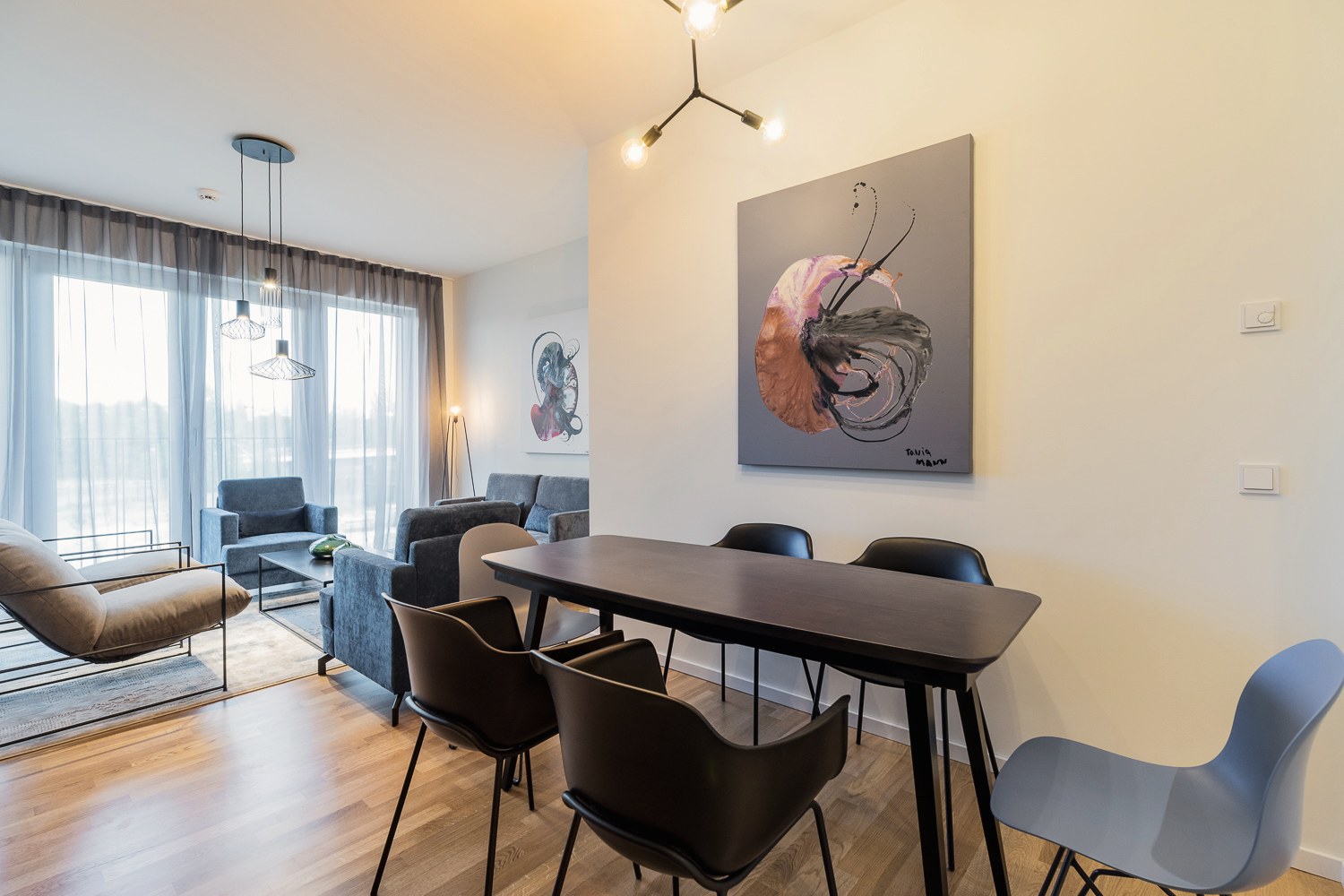 Essbereich mit dunklem Tisch und Wohnbereich mit Sofas