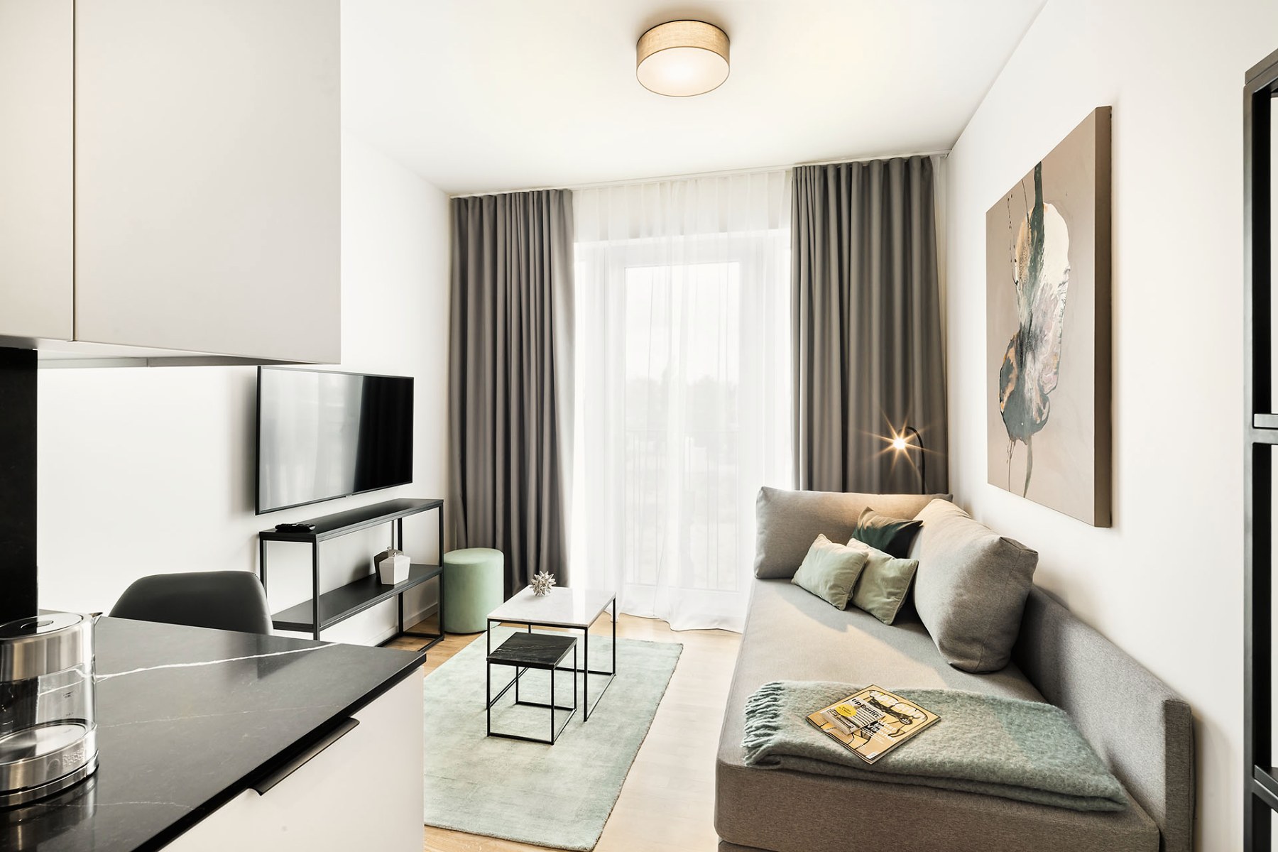 Helles Studio mit Sofa, Kochzeile und Wandbild